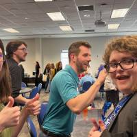 Two event attendees smiling and giving thumbs up to camera